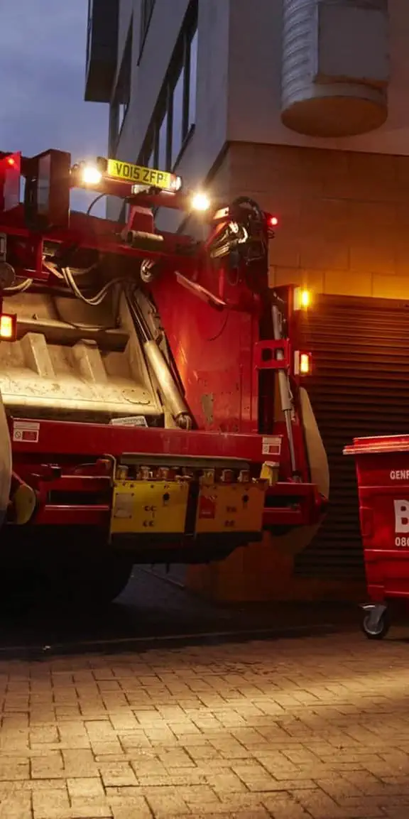 Biffa truck and bin outside building at night