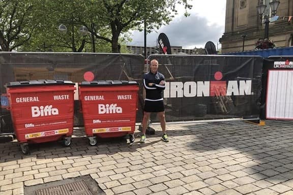 Nigel Carr next to Biffa bins and Ironman logo