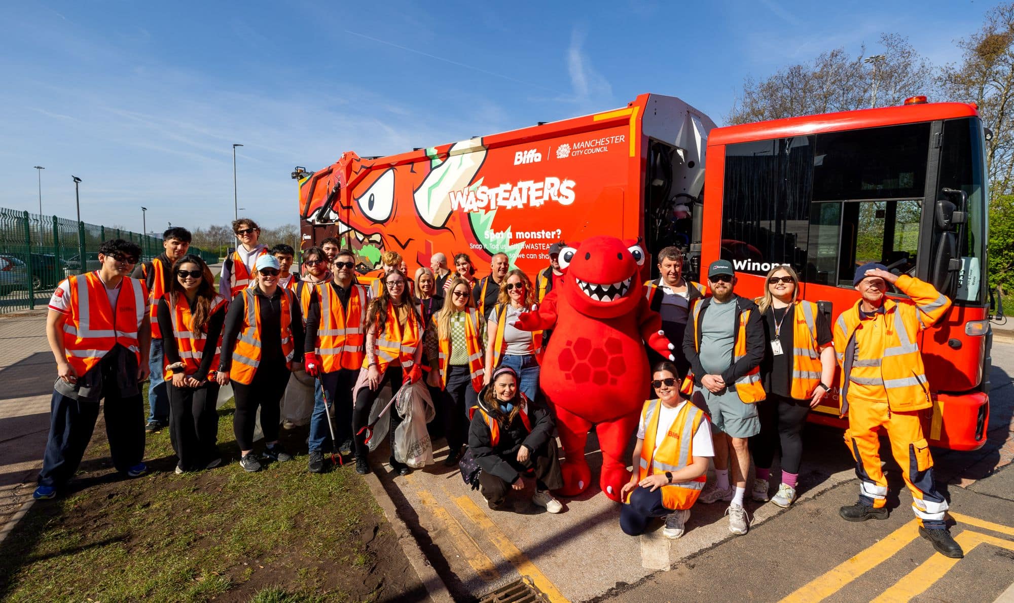 Group of litter pickers standing with wasteater mascot in front of wasteater truck