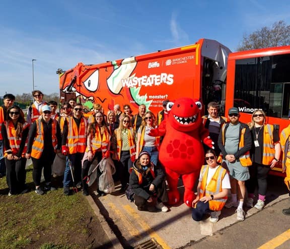 Group of litter pickers standing with wasteater mascot in front of wasteater truck