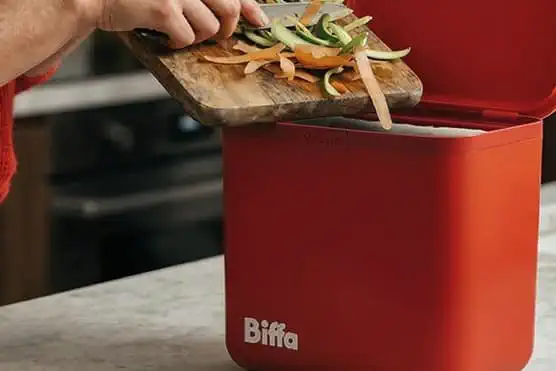 Food being scrapped into red kitchen caddy