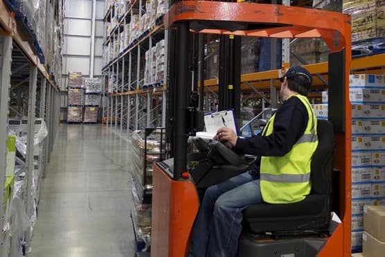 Worker in forklift in warehouse