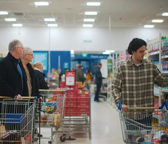 Man and couple in Community shop aisle