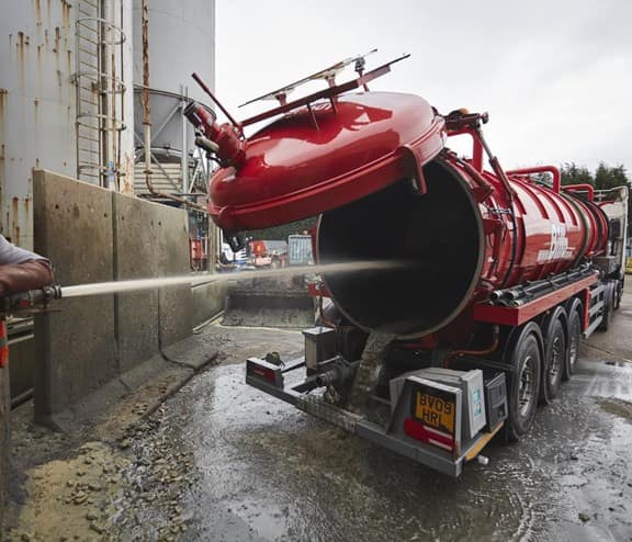 worker jet washing back of a tanker