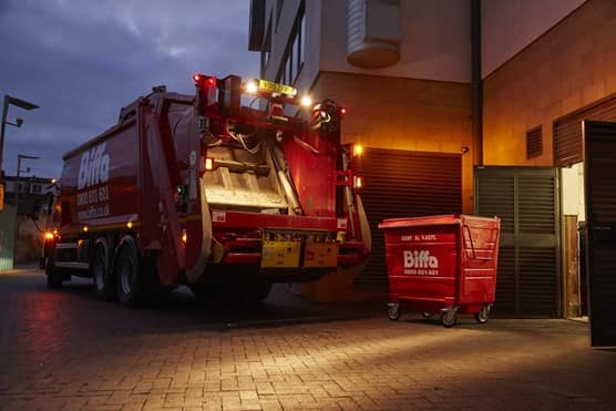 Biffa truck and bin outside building at night
