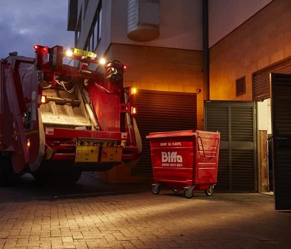 Biffa truck and bin outside building at night