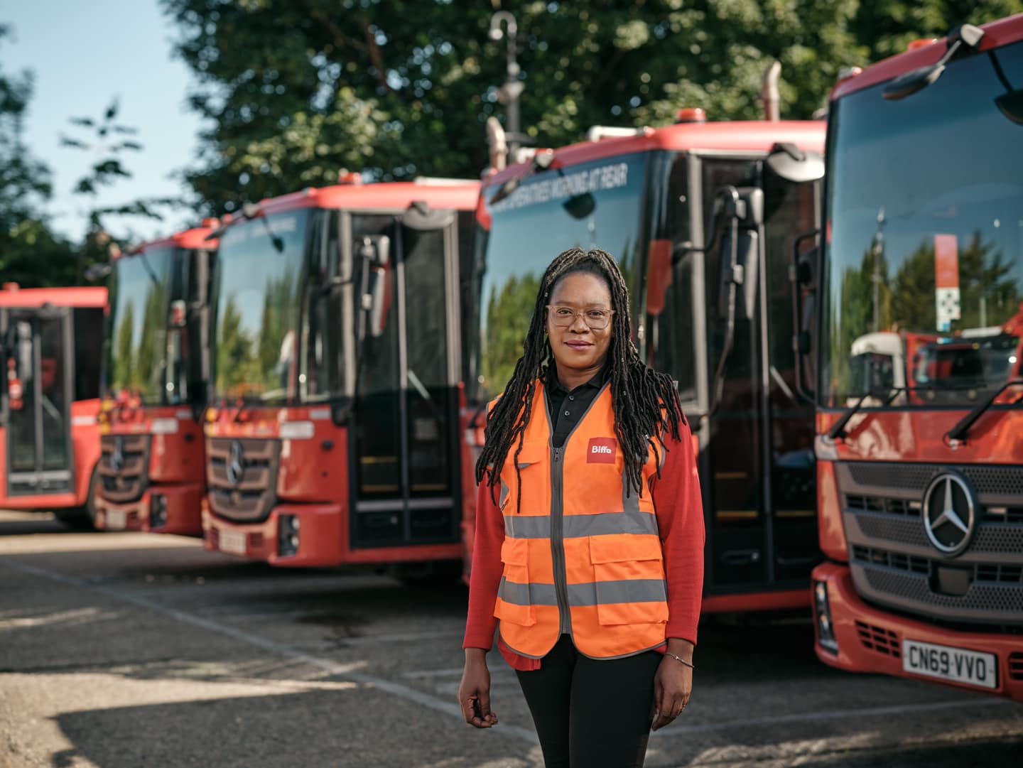 Female employee in front of waste vehicles