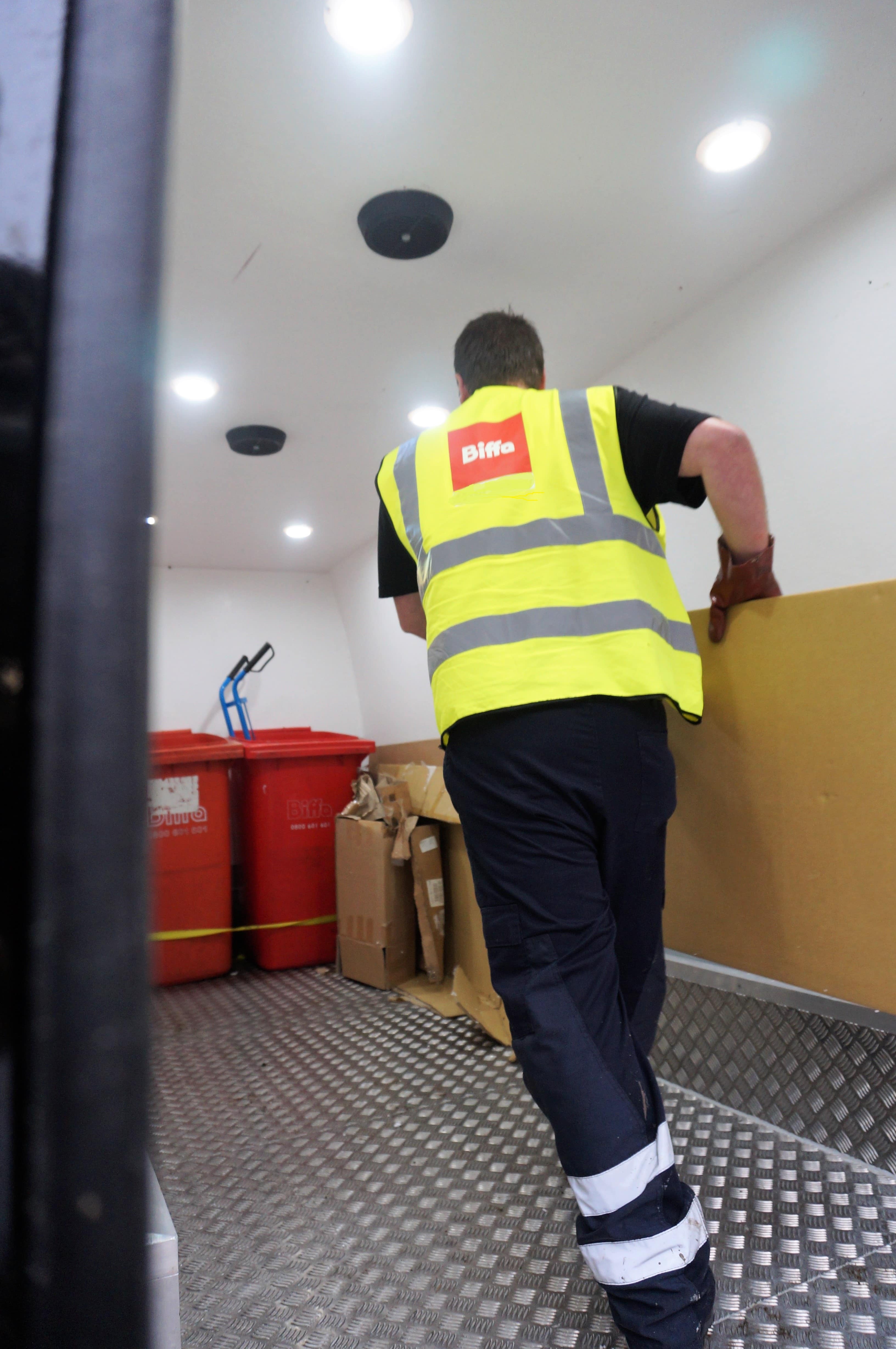 Biffa worker carrying cardboard in van
