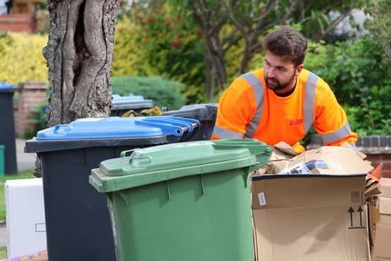 Biffa employee collecting bins in East Sussex after Biffa extends waste collection and cleaning contract