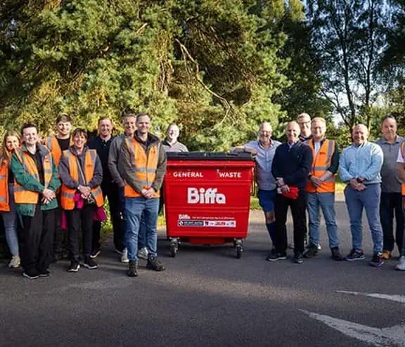 Group of volunteers from local businesses and community picking litter from woodland