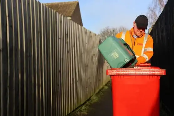 Employee emptying bin into a bin