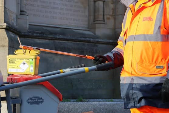 Employee handling clinical waste bin