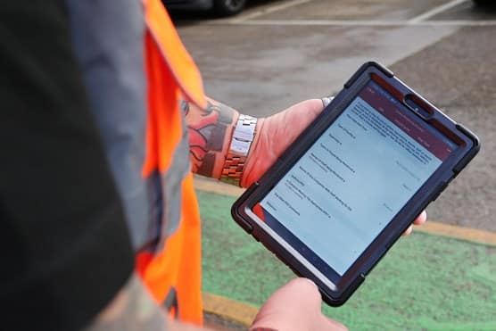 Employee holding safety monitoring form on iPad