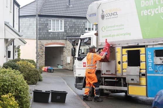 Employee loading bin bag into the back of truck