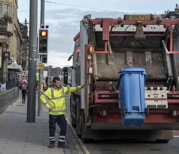 Man in high vis lifting bin into waste truck