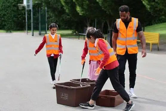 School children collecting rubbish with volunteers