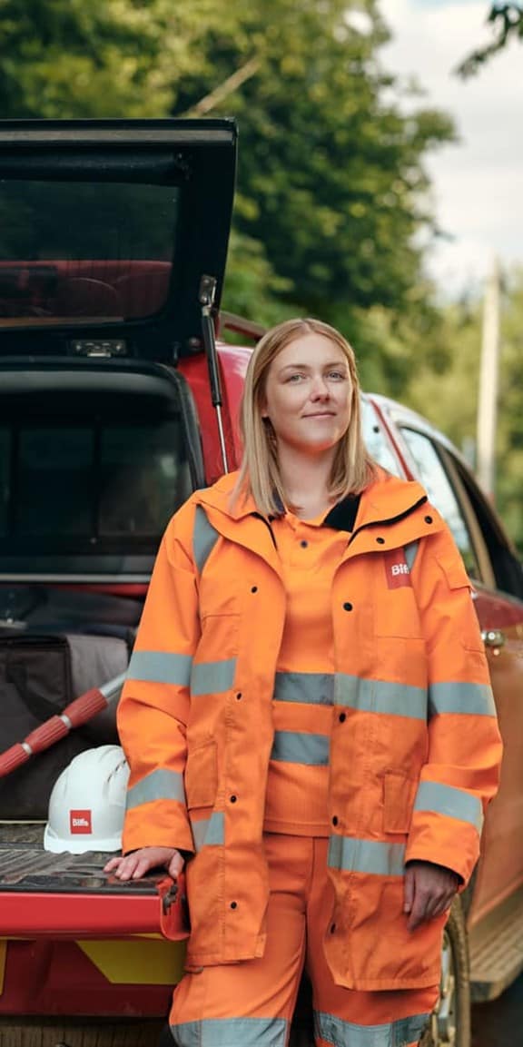 Female employee in high vis standing with car boot open