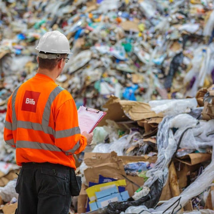 Person in Biffa high vis looking at mountain of waste
