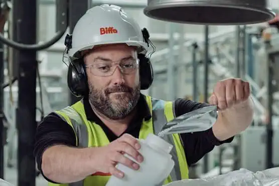 Male Biffa employee scooping pellet granules into container