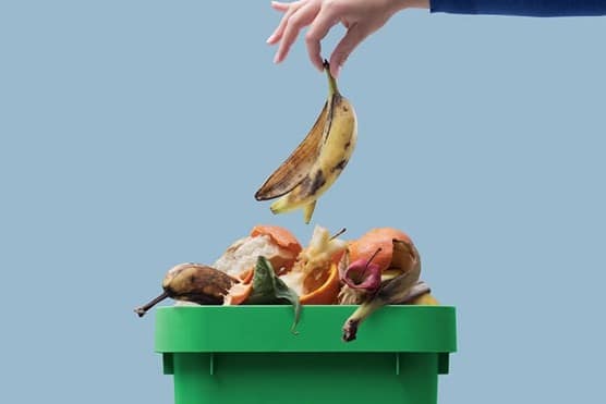 Hand dropping banana peel in bin