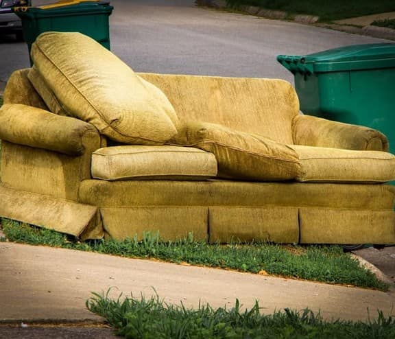 Old yellow couch with cushions on a curb