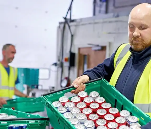 Man in high vis working with cans in a warehouse